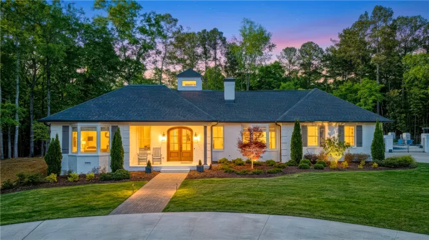 A graceful home framed by mature trees, features a brick paver walkway leading to its inviting entrance.