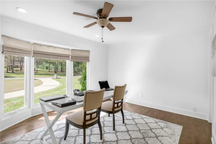 A well-lit home office with large windows provides a tranquil workspace.