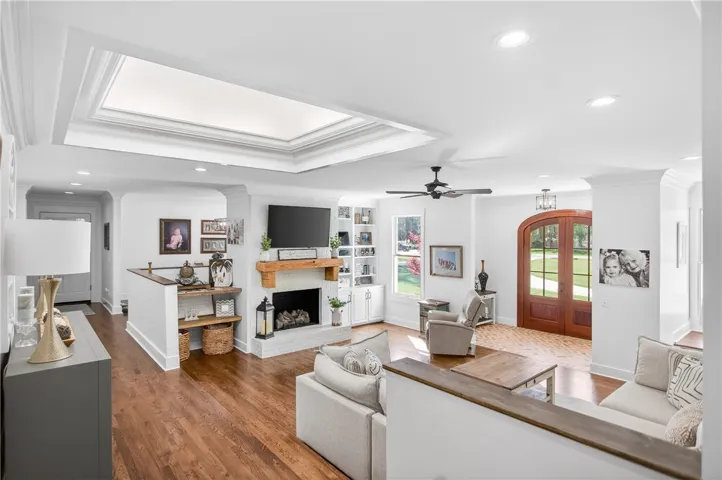 A welcoming living area showcases rich hardwood floors, a cozy fireplace, and an elegant arched entryway.