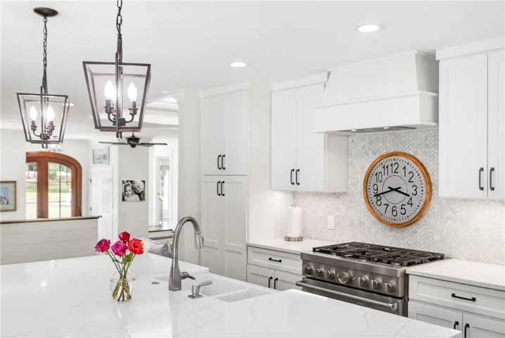 A well-appointed kitchen features a large island with a sink, recessed lighting, and a modern range.