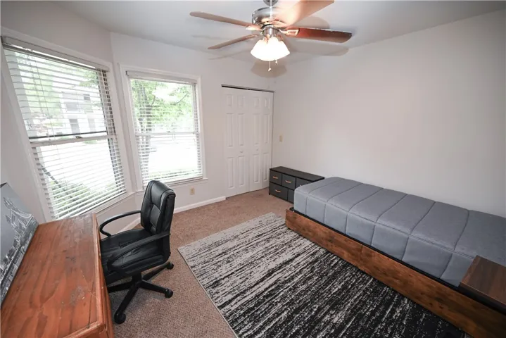 Functional bedroom featuring a ceiling fan, abundant natural light, and ample closet storage.