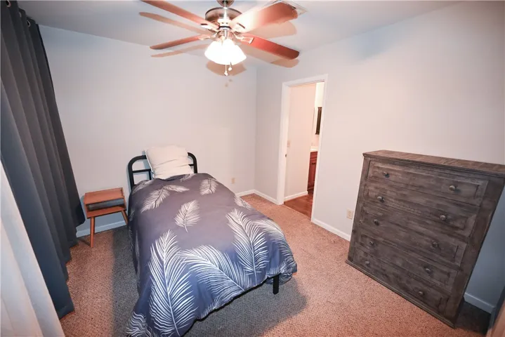 Comfortable bedroom with neutral carpeting and a ceiling fan for year-round comfort.
