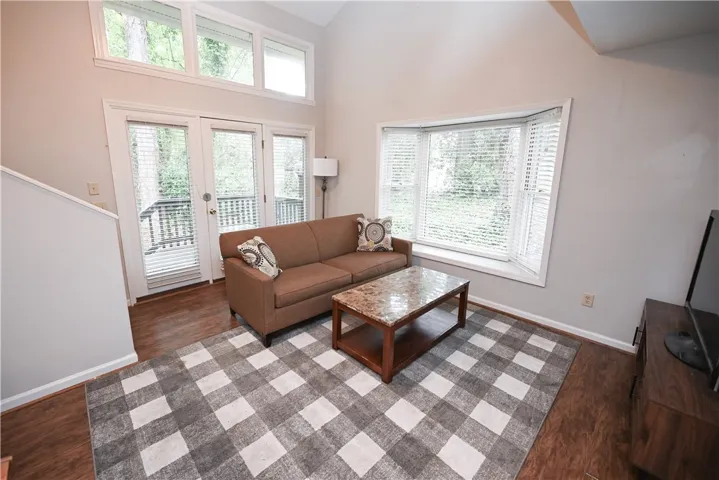 A naturally illuminated living room features gleaming hardwood floors and soaring vaulted ceilings.