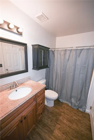 A well-appointed bathroom features a single vanity with stone counters and rich wood cabinetry.