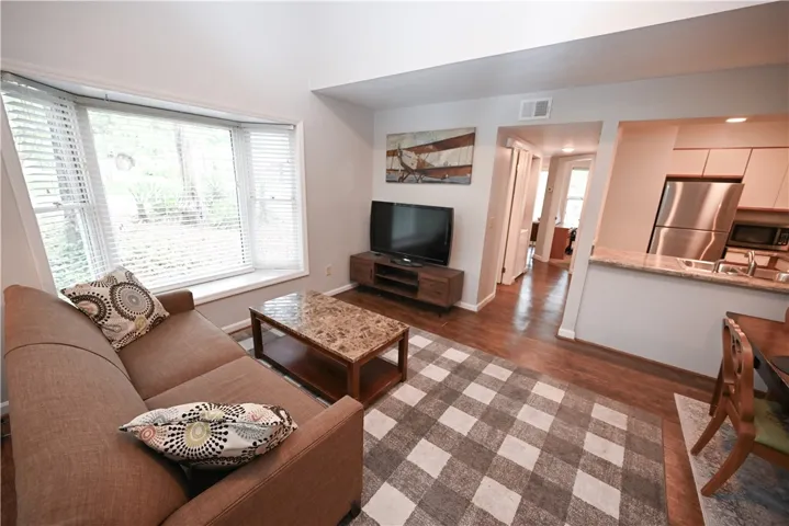 A welcoming living area with rich hardwood floors and a light-filled bay window.