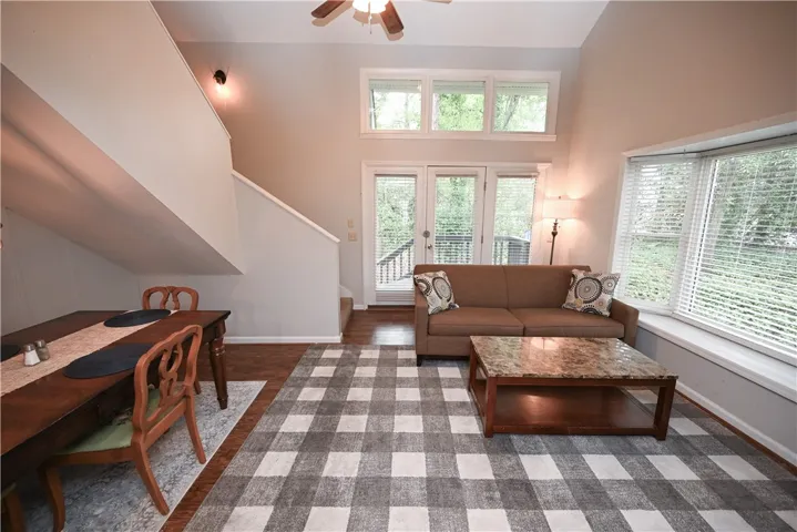 A well-lit living area features tall ceilings and warm wood floors, leading to an outdoor deck.