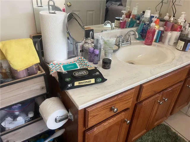 A well-lit vanity with a sleek countertop and rich wood cabinetry, offering ample storage.