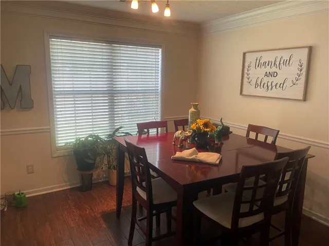 Rich hardwood flooring complements crown molding and abundant natural light in this refined dining area.