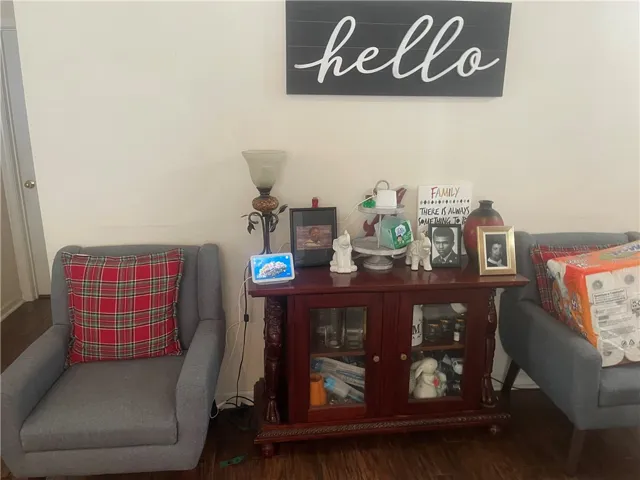 Well-lit living area features a warm wooden cabinet and inviting armchairs.