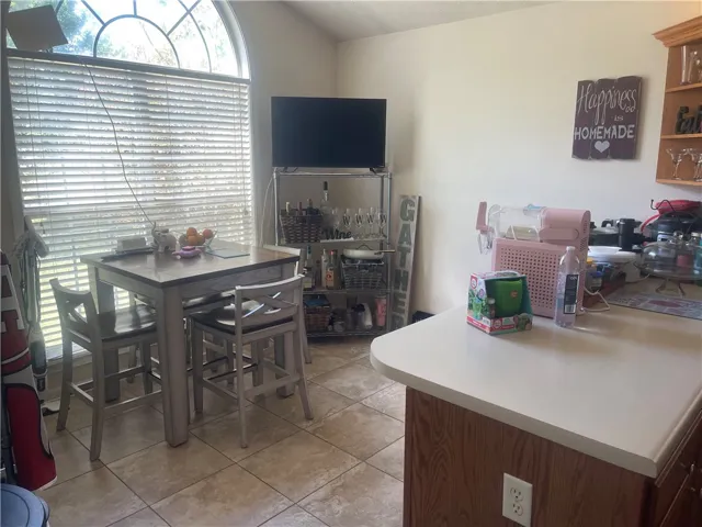 A well-lit kitchen area features a breakfast bar with seating and a large arched window.