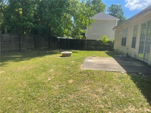 A spacious backyard with mature trees and privacy fencing, perfect for outdoor activities.