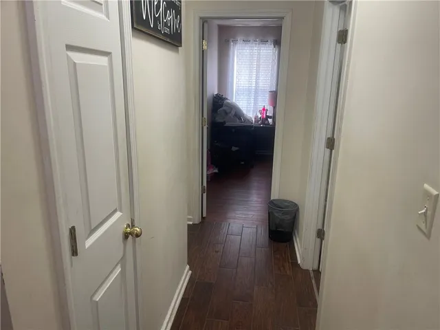 A well-maintained hallway with rich hardwood-look flooring leads to a cozy room.