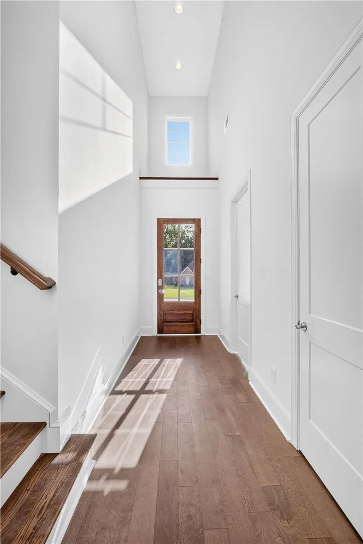 Enter into a bright, two-story foyer with gleaming hardwood floors and a striking wooden front door.