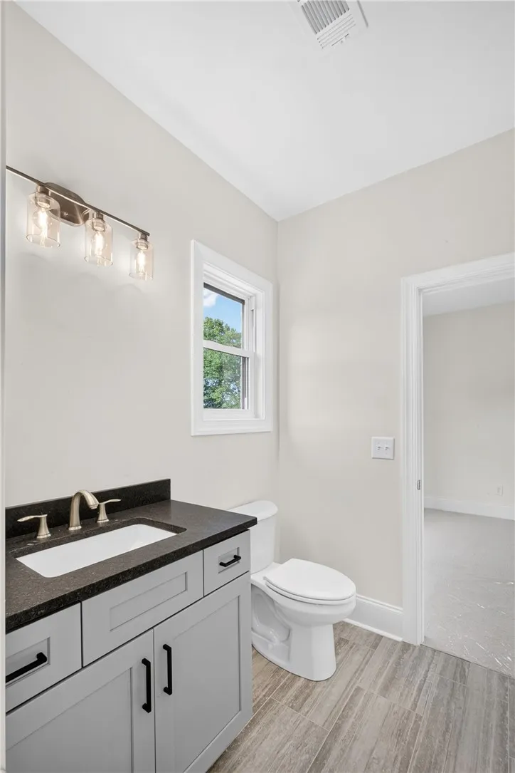 A well-lit bathroom showcases a modern vanity with dark counters and stylish flooring.