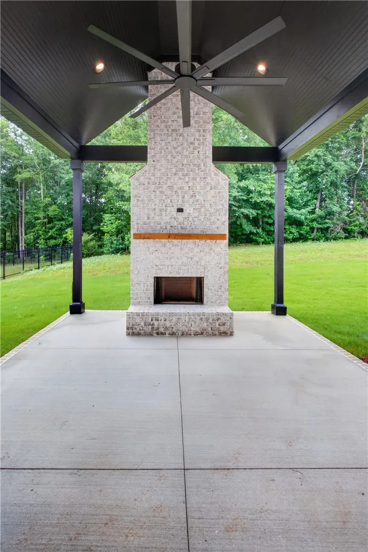 An inviting outdoor patio offers a brick fireplace and an outdoor ceiling fan for comfort.