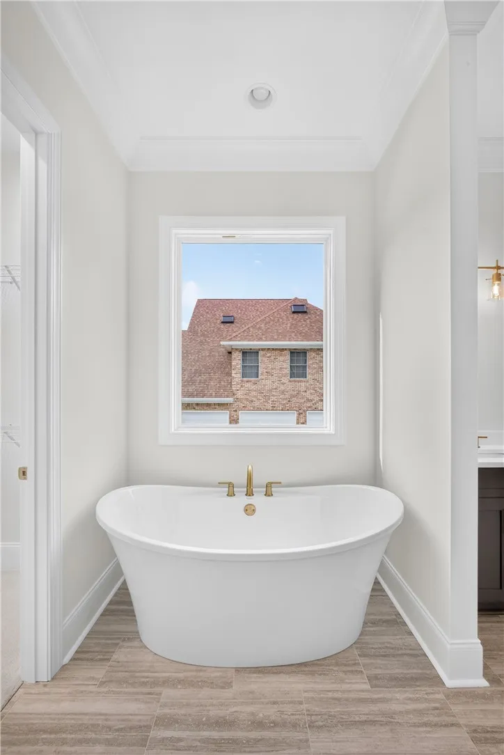Indulge in a tranquil soak within this pristine, standalone tub, set against warm wood-look tile.
