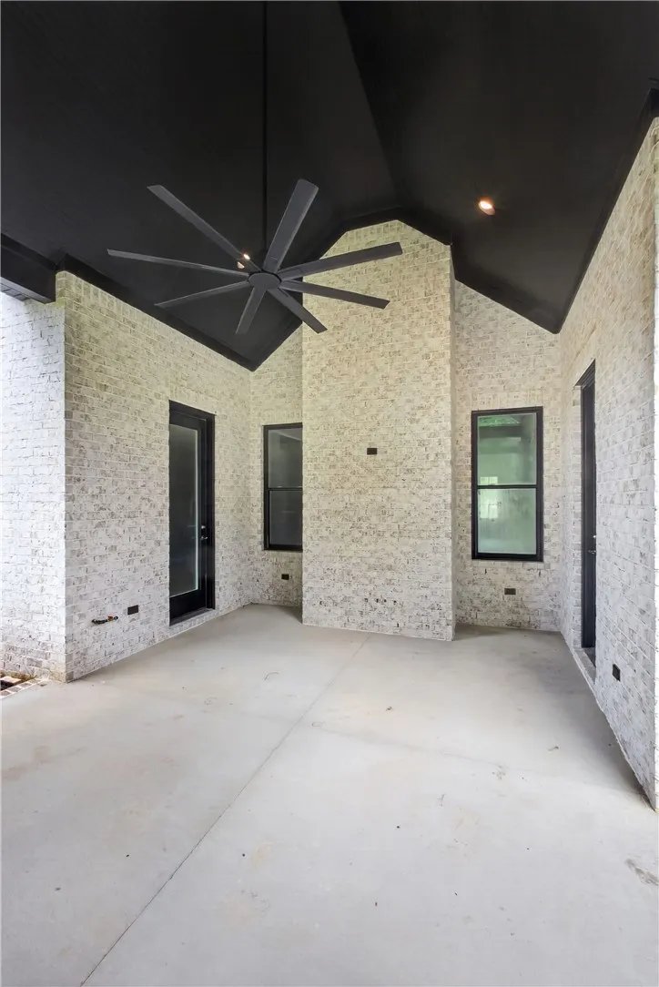 An inviting covered patio featuring a distinctive black vaulted ceiling and whitewashed brick walls.