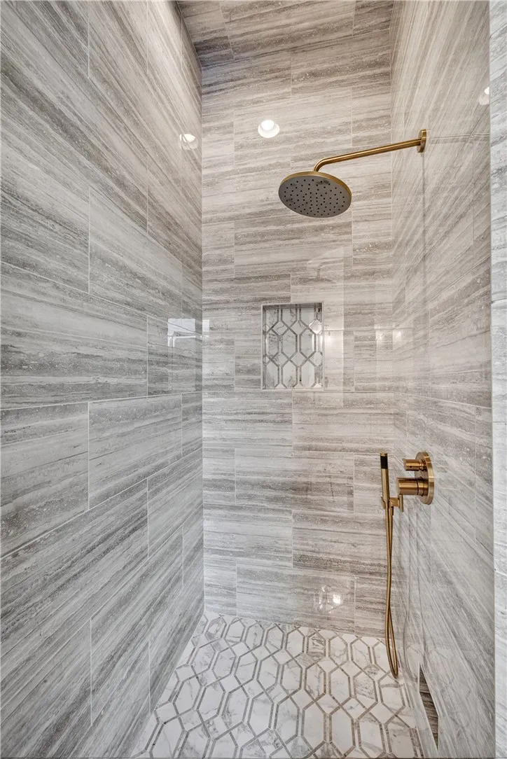 Rainfall shower head and intricate tile work define this luxurious bathroom space.