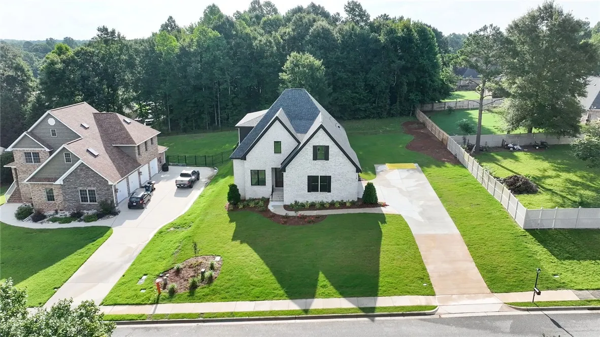 A striking white brick home with dark trim offers pristine curb appeal and a spacious front yard.