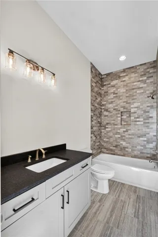 A well-appointed bathroom offers sleek white cabinetry, dark stone counters, and a modern tiled shower-tub combination.
