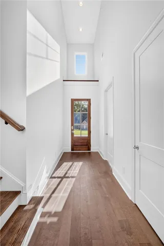Enter into a bright, two-story foyer with gleaming hardwood floors and a striking wooden front door.