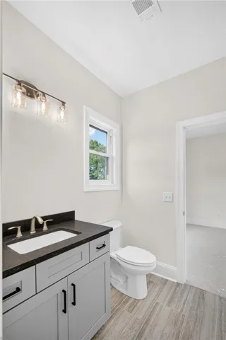 A well-lit bathroom showcases a modern vanity with dark counters and stylish flooring.