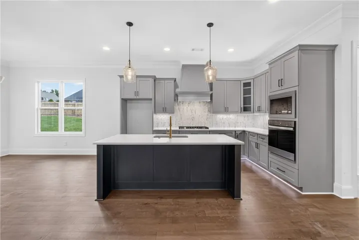 A gourmet kitchen offers a spacious island with sink, ample cabinetry, and rich hardwood flooring throughout.
