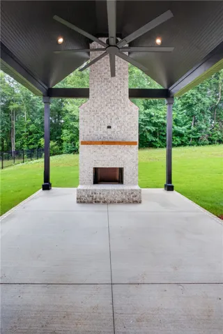 An inviting outdoor patio offers a brick fireplace and an outdoor ceiling fan for comfort.