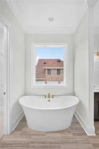Indulge in a tranquil soak within this pristine, standalone tub, set against warm wood-look tile.
