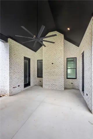 An inviting covered patio featuring a distinctive black vaulted ceiling and whitewashed brick walls.