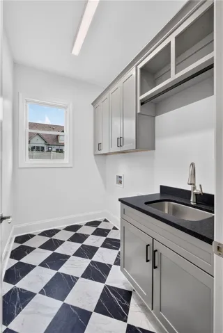 Bold checkered flooring and sleek cabinetry elevate this functional laundry space.