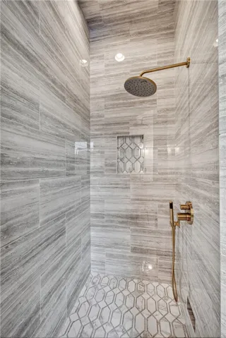 Rainfall shower head and intricate tile work define this luxurious bathroom space.