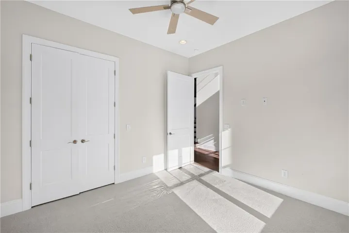A quiet bedroom features soft carpeting and a ceiling fan for optimal comfort.