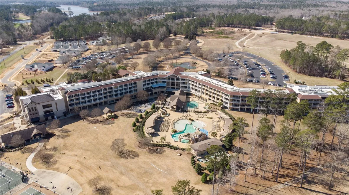 An aerial perspective reveals a vast resort complex nestled amidst mature trees and a distant lake.