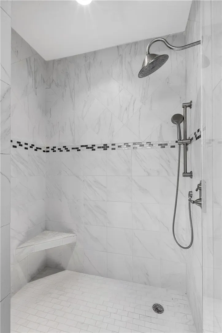 Indulge in a rejuvenating shower experience with this elegantly tiled enclosure featuring a convenient corner bench.