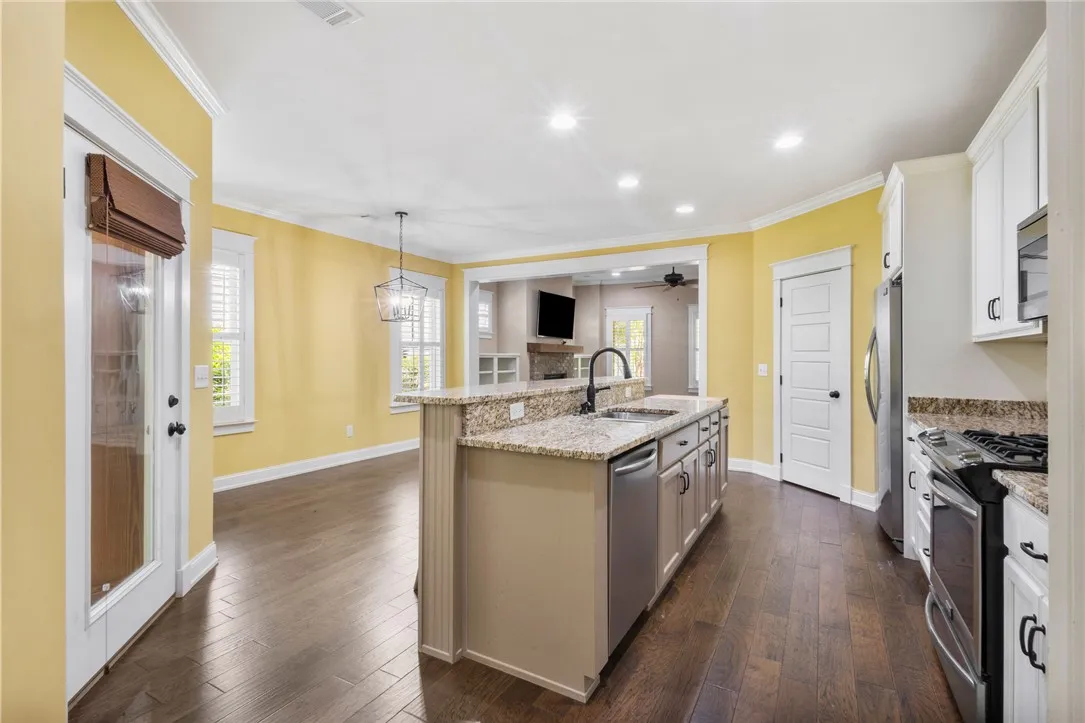 A chef's kitchen boasts a generous island with granite counters, seamlessly connecting to an inviting living space.
