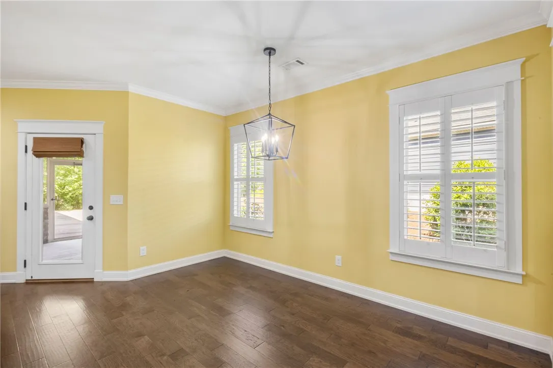 Wood floors and bright walls define this welcoming dining room, illuminated by a contemporary hanging light.