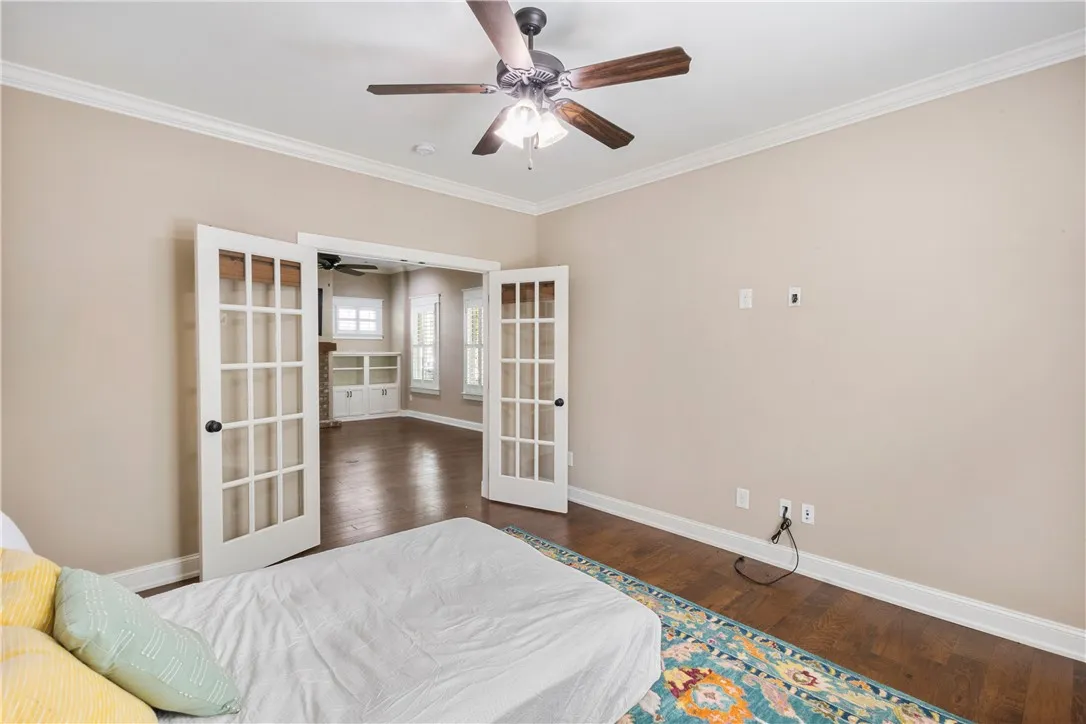 French doors open into this versatile bedroom featuring a ceiling fan and wood floors.