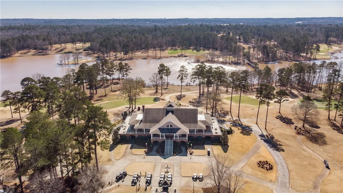 An aerial panorama reveals a grand club house nestled beside a shimmering lake, surrounded by a meticulously manicured golf course.
