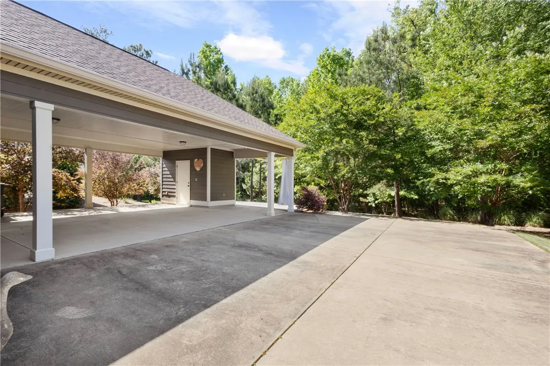 A spacious concrete driveway leads to a covered carport, offering ample parking and protection.