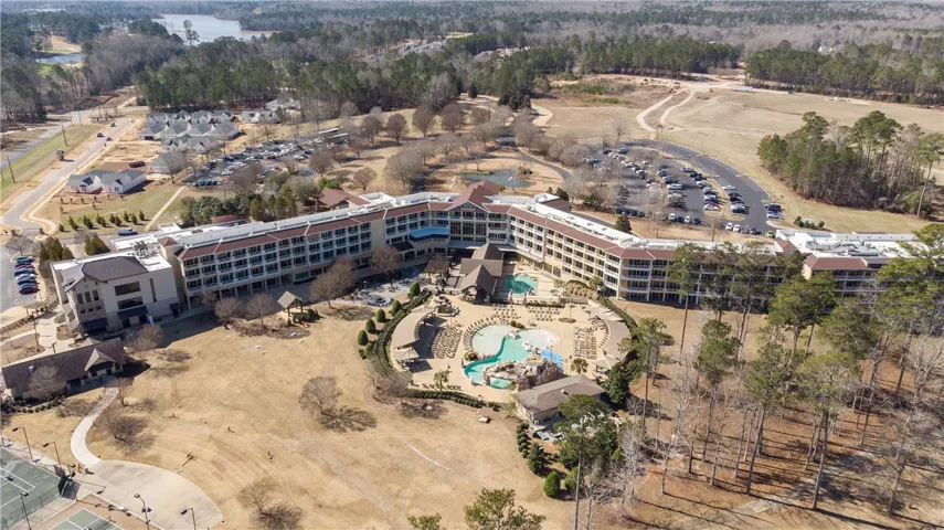 An aerial perspective reveals a vast resort complex nestled amidst mature trees and a distant lake.