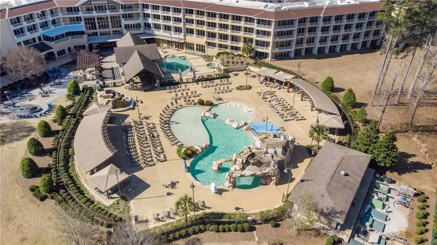 An aerial perspective reveals a sprawling resort pool complex with extensive lounge areas and lush landscaping.