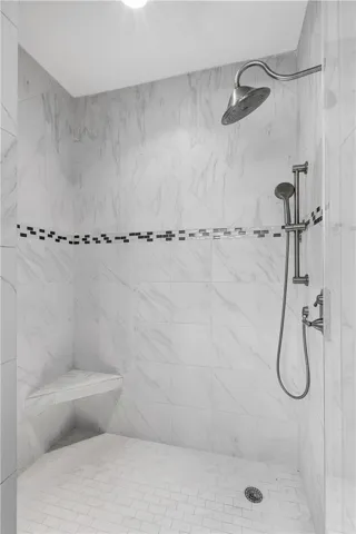 Indulge in a rejuvenating shower experience with this elegantly tiled enclosure featuring a convenient corner bench.