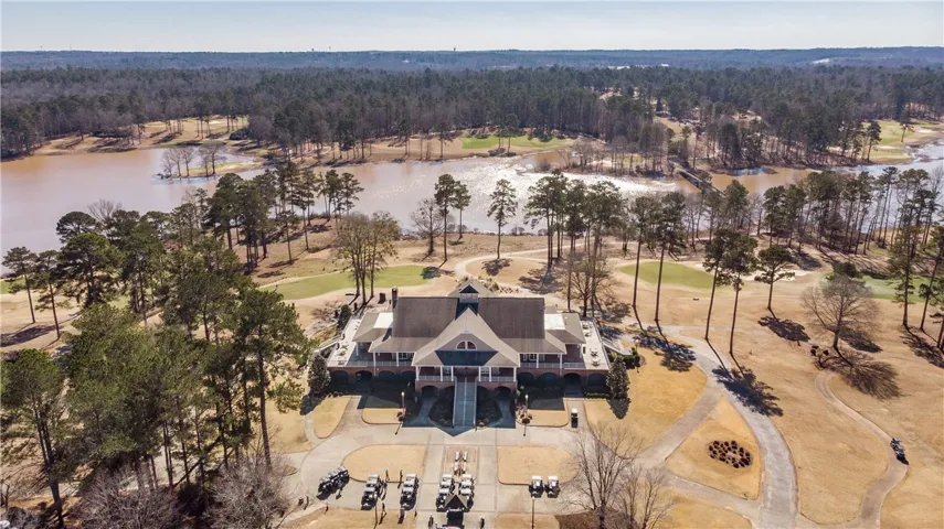 An aerial panorama reveals a grand club house nestled beside a shimmering lake, surrounded by a meticulously manicured golf course.