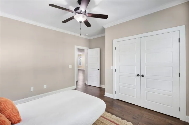 A comfortable bedroom features rich wood flooring and a stylish ceiling fan.