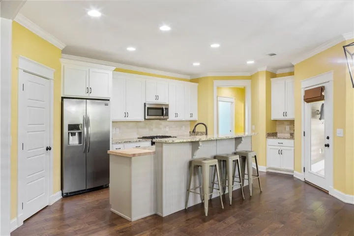 A vibrant eat-in kitchen with wood flooring and stainless steel appliances.