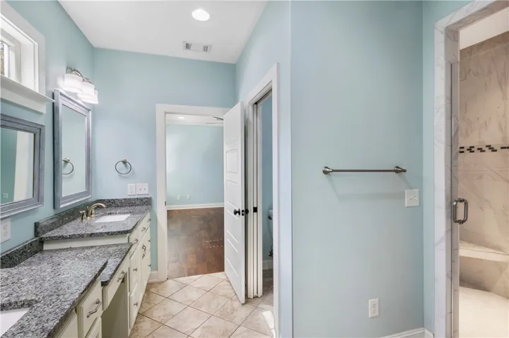 A well-appointed bath boasts dual vanities with granite countertops and a spacious walk-in shower.