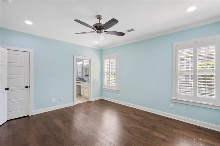 Wood floors and a ceiling fan complete this comfortable bedroom space.