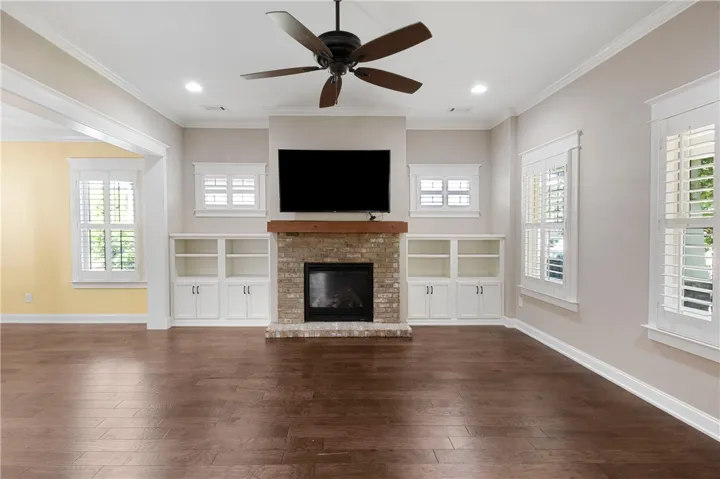Rich wood floors complement the inviting fireplace with built-in shelving, creating a focal point for any gathering.