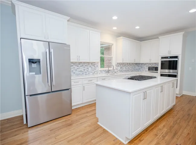 Culinary delights await in this bright kitchen with a spacious island, integrated appliances, and lustrous wood flooring.